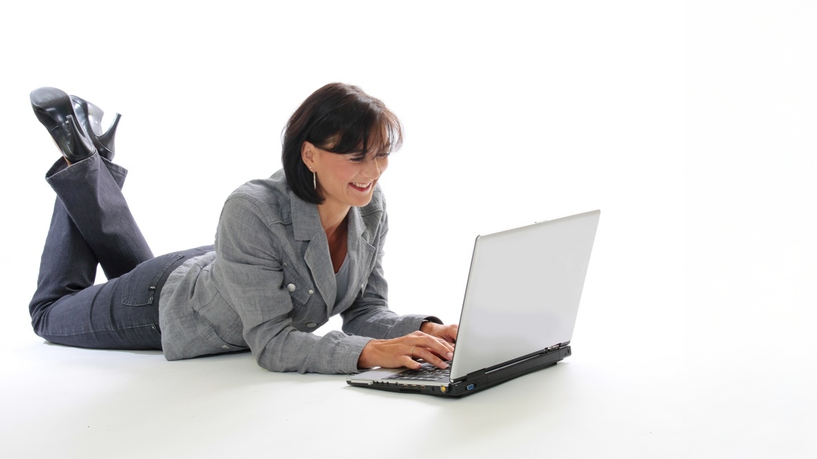 Eine Fachfrau schaut lächelnd auf ihren Laptop