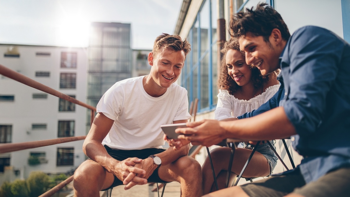 Trois jeunes professionnels regardent une vidéo ensemble sur un smartphone